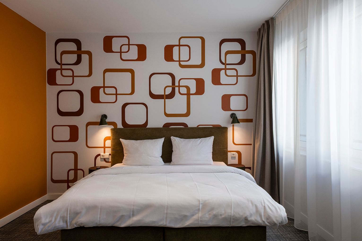Apartment mit großem Bett, Fenster und orangefarbener Wand