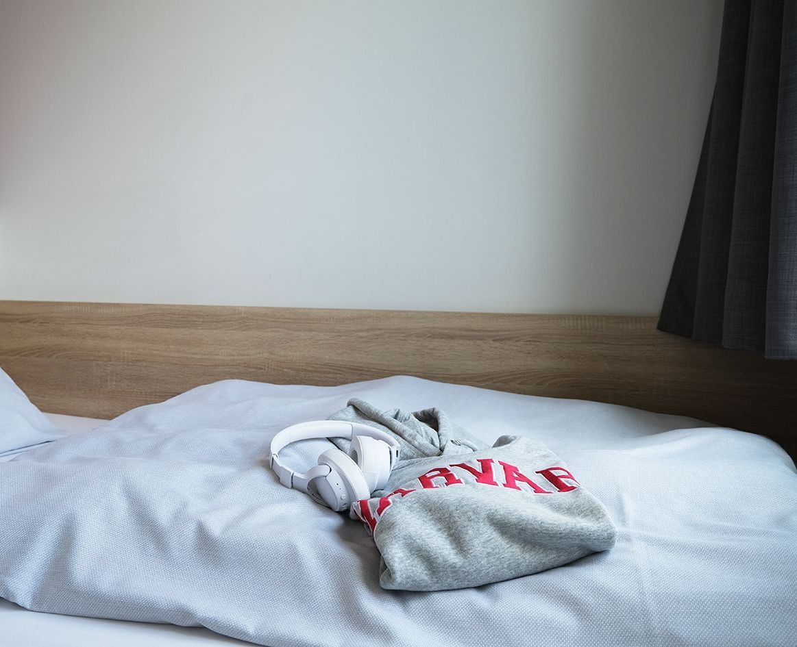 Ein Bett mit einer Decke und Kopfhörern darauf.