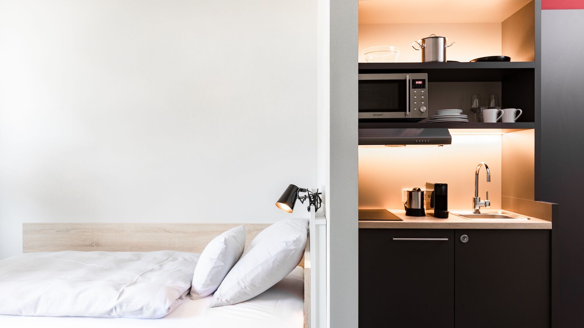 Ein Schlafzimmer mit einem Bett und eine Küche mit Mikrowelle und Spüle.