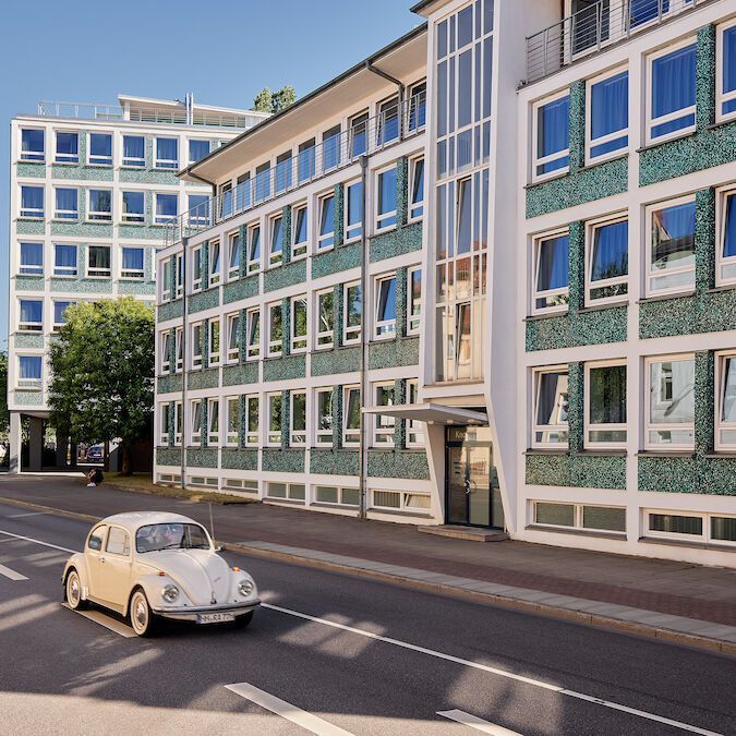 Ein Auto fährt eine Straße vor einem großen Gebäude entlang