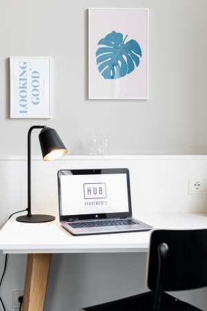 Auf einem Schreibtisch steht neben einer Lampe ein Laptop.