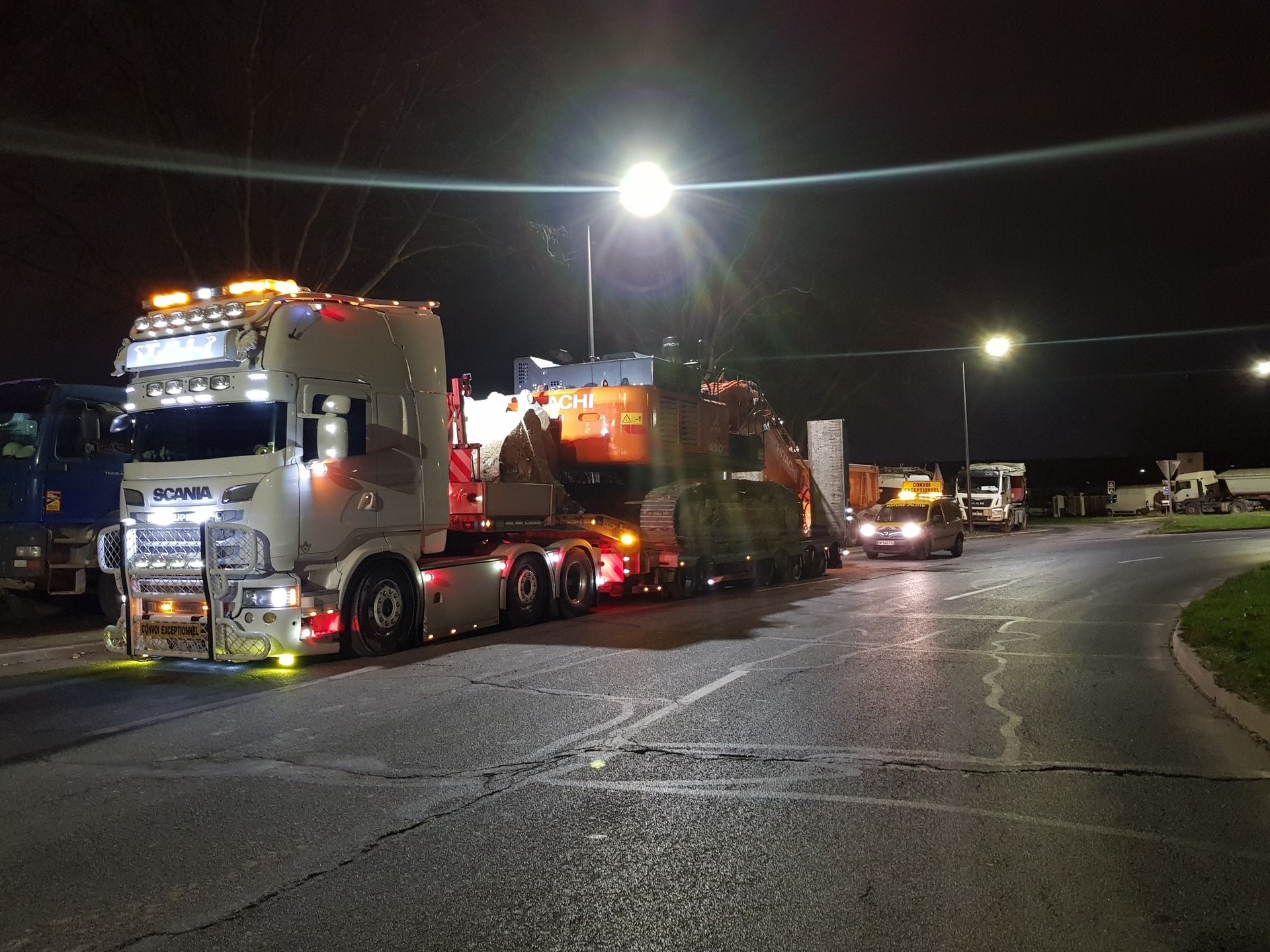 Un camion transportant un grand engin de chantier sur une route de nuit