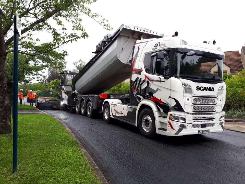 Camion-benne Scania sur une route à l'enrobage en cours de pose