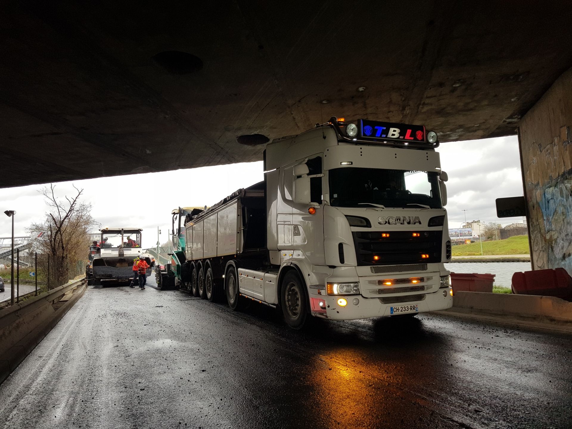 Camion-benne Scania sous le pont d'une autoroute