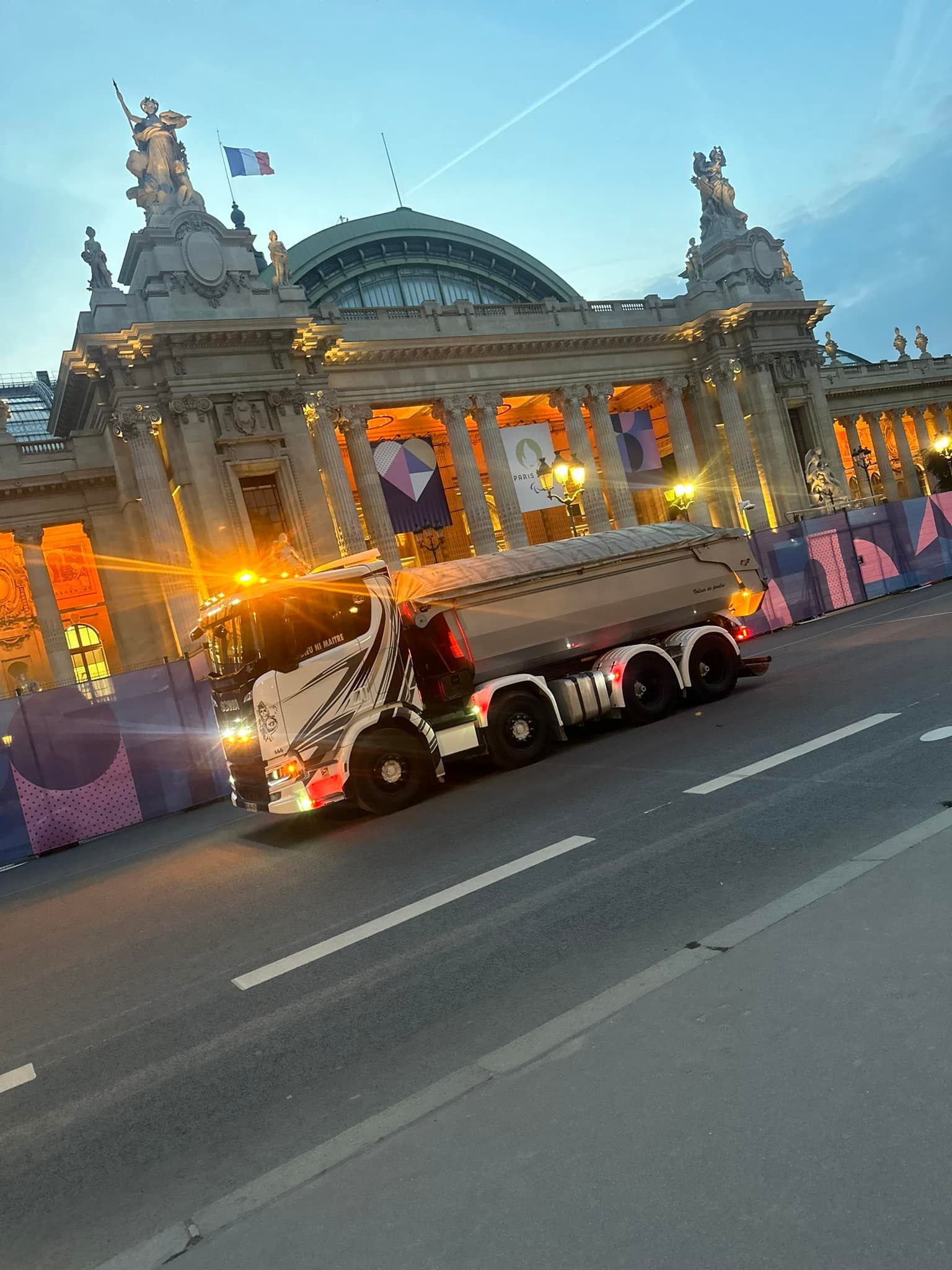 Camion-benne passant devant un bâtiment public