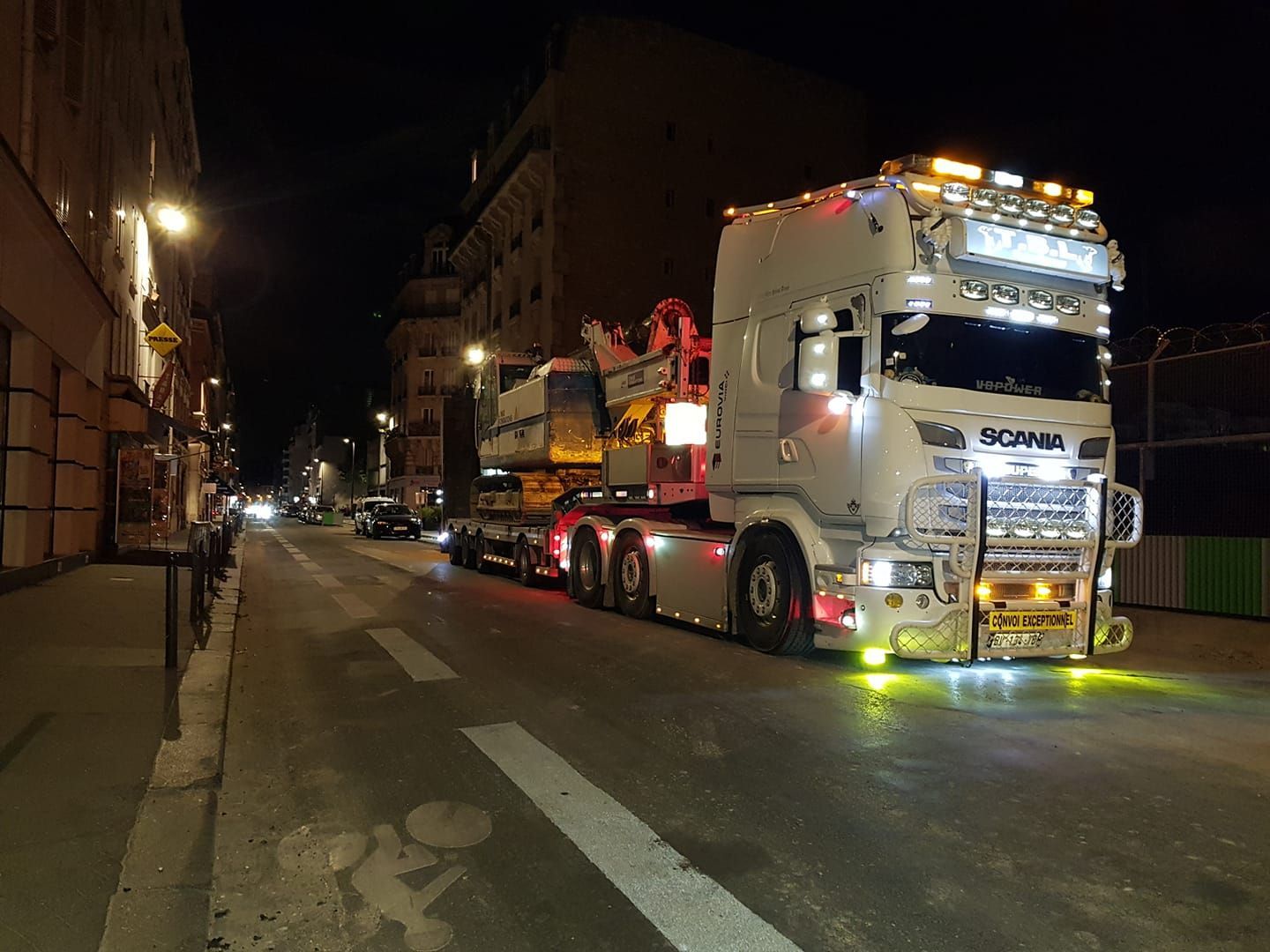 Camion blanc transportant des engins de chantier en ville, de nuit