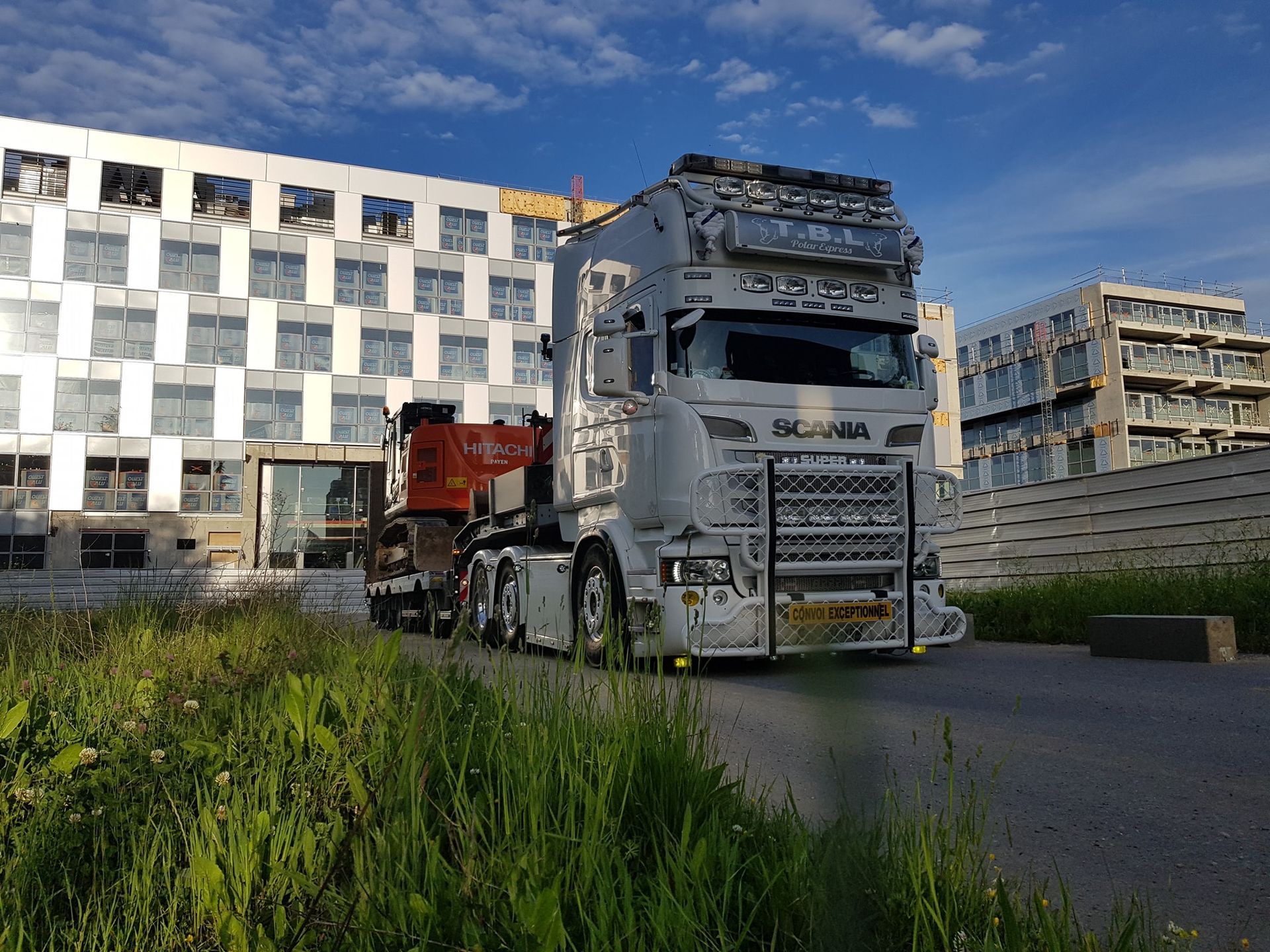 Poids lourd en convoi exceptionnel devant un très haut bâtiment