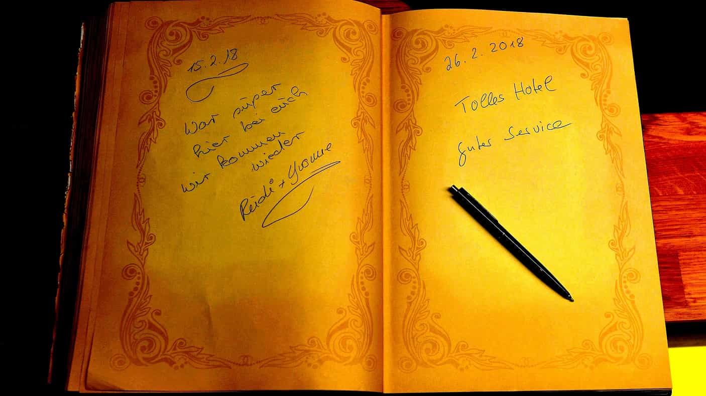 Ich schlage ein altes Buch mit handgeschriebenen Einträgen auf; der Stift liegt auf der rechten Seite.