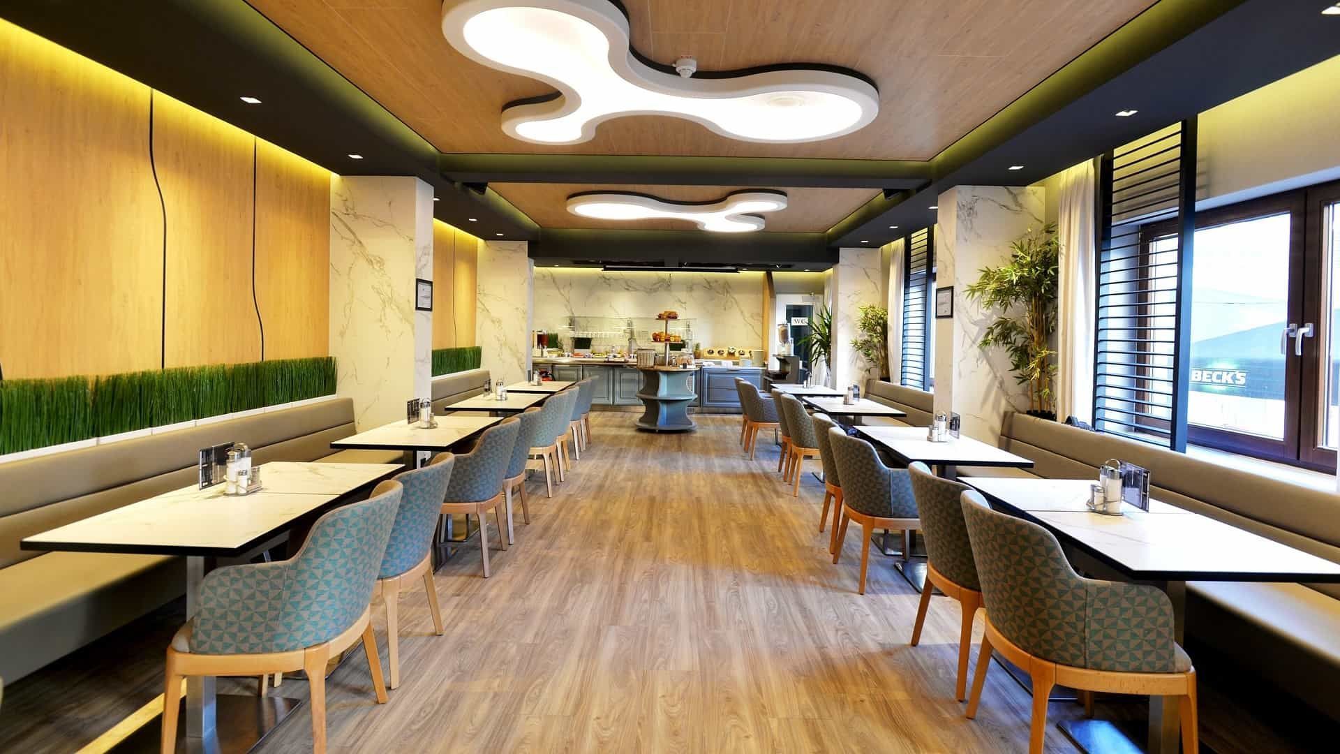 Restaurantinterieur mit Tischen, Stühlen und Buffetstation im modernen Holzdesign.