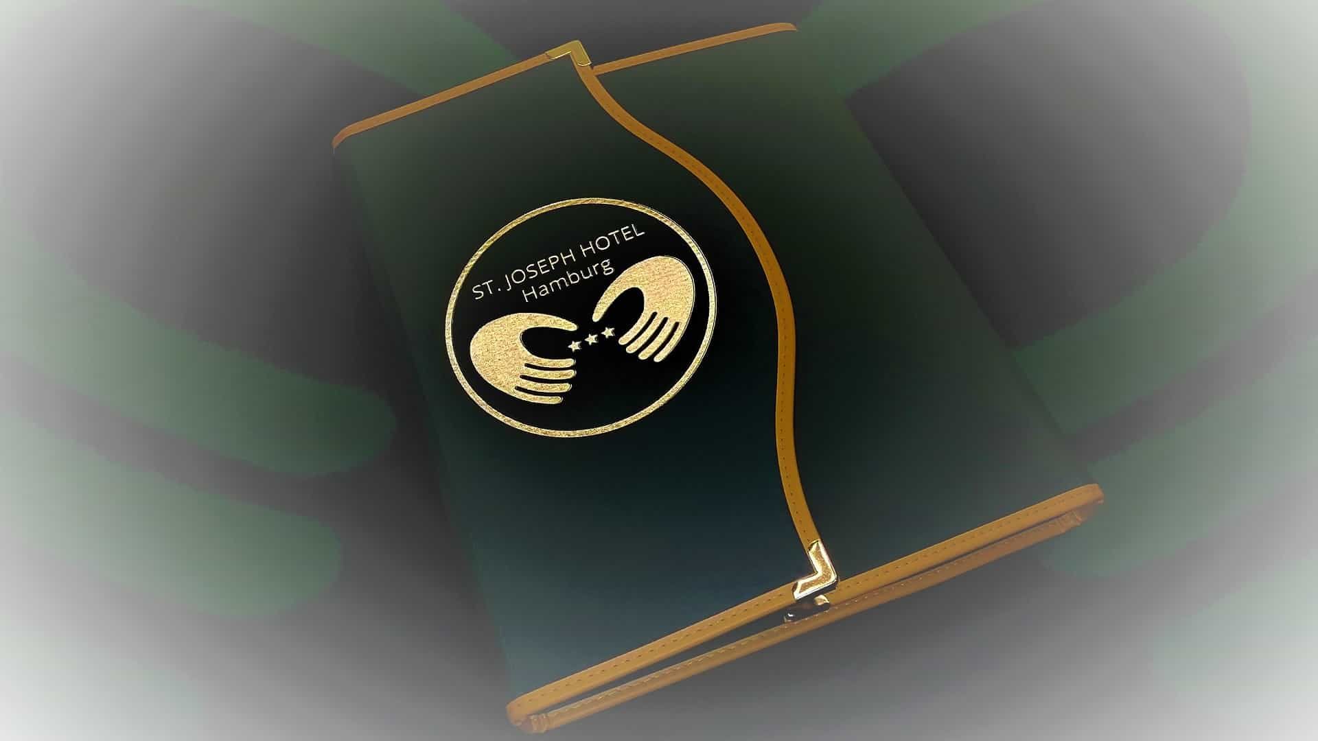 Dunkelgrüne Hotelkarte mit goldenem Rand und Logo: zwei stilisierte Hände.