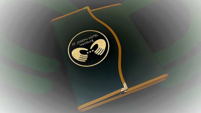 Dunkelgrüne Hotelkarte mit goldenem Rand und Logo: zwei stilisierte Hände.