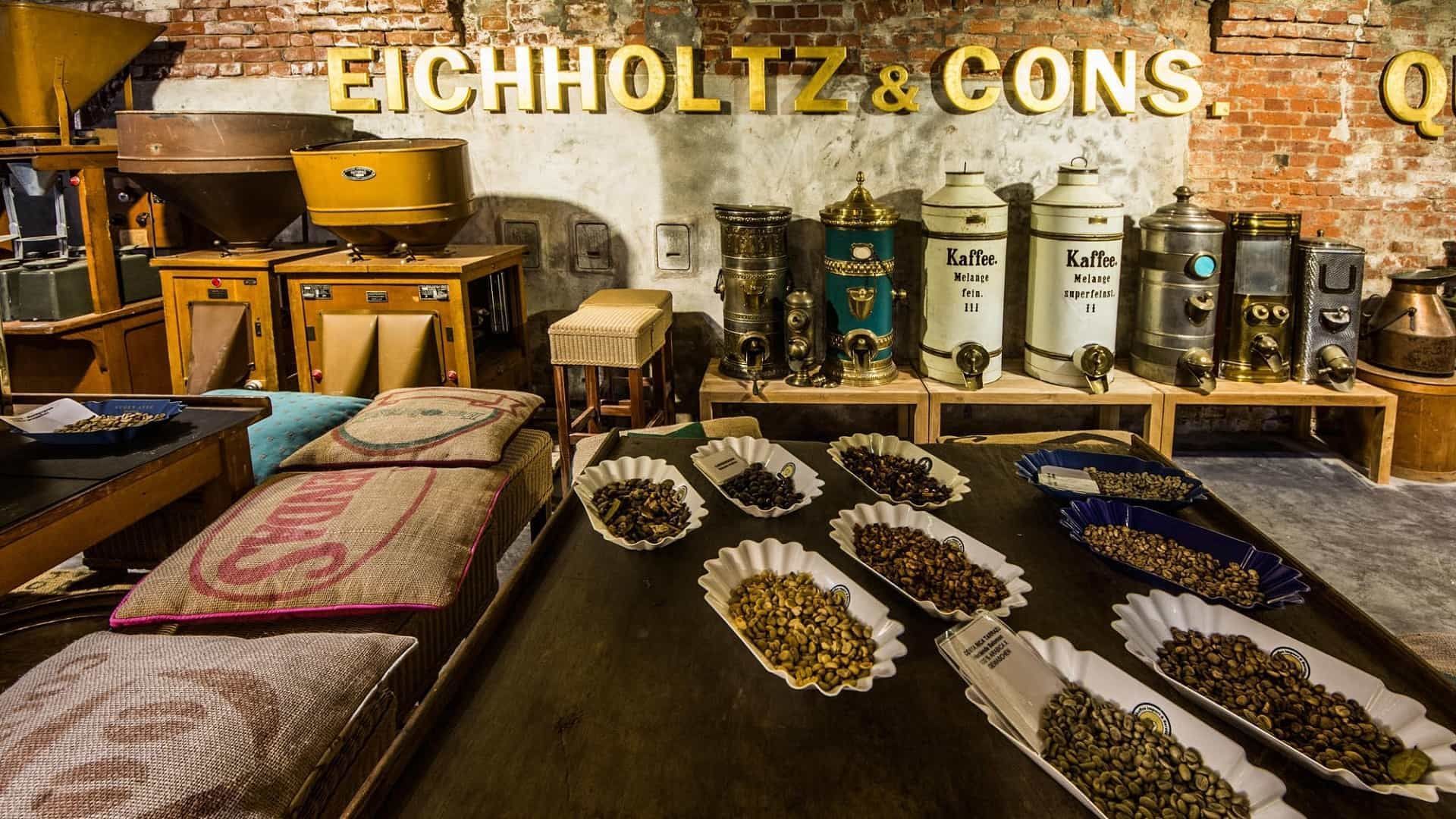 Antike Kaffeeauslage mit gerösteten Bohnen, Kaffeemühlen und Dosen. Darüber das Schild „Eichholtz & Cons.“
