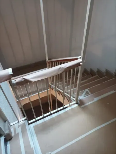 Una escalera con una barandilla fijada al suelo con cinta adhesiva