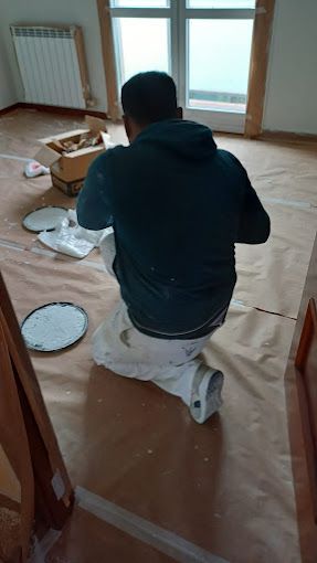 Un hombre con una camisa azul está enyesando una pared.