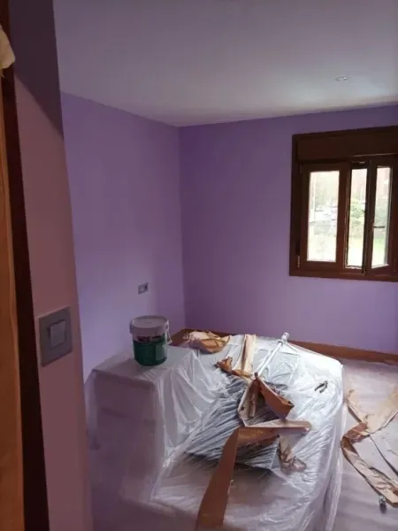 Se está pintando un dormitorio con paredes moradas.