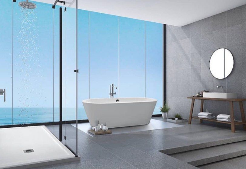 Baño moderno minimalista con bañera independiente, ducha de cristal y ventanas con vistas al mar.