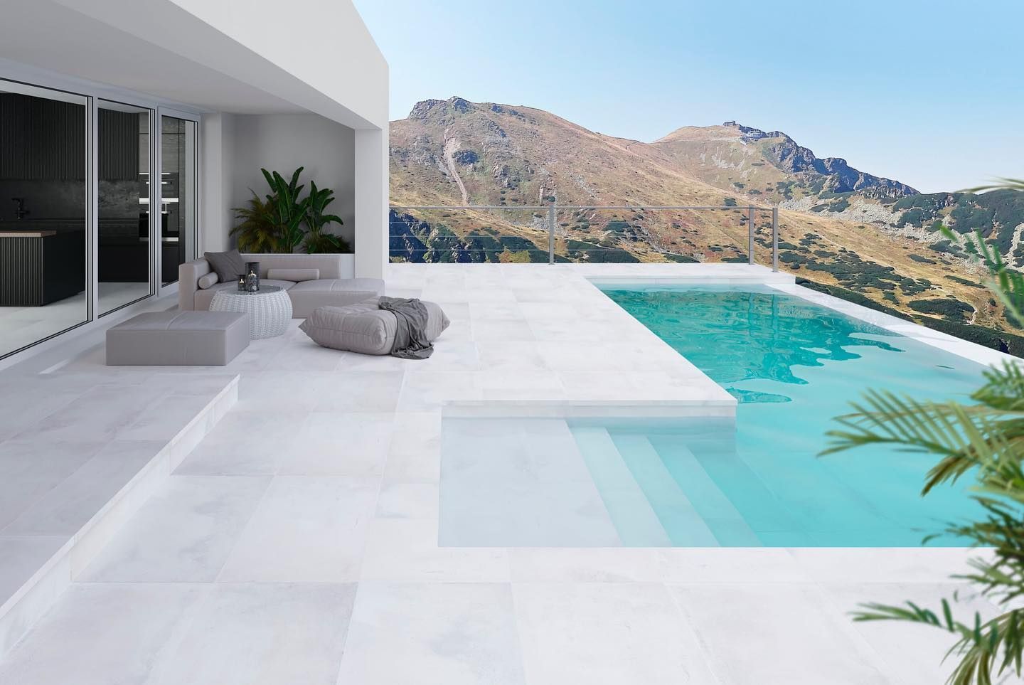 Terraza de villa moderna blanca con piscina infinita de color turquesa y vistas a la montaña.