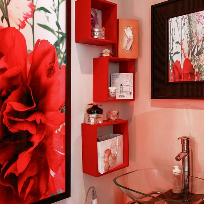 Petit espace de soins avec étagères rouges contenant des produits et accessoires de beauté.