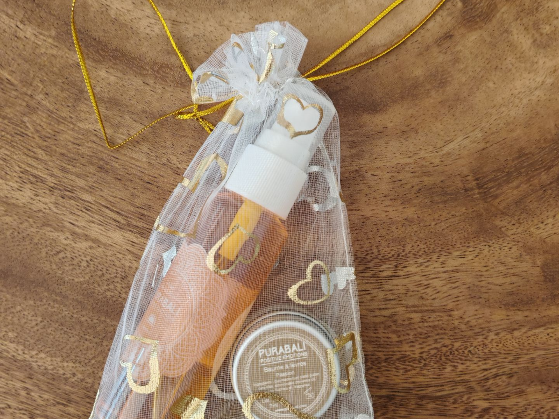 Petit coffret cadeau avec produits de beauté Pura Bali dans un sachet en organza blanc à motif de cœurs dorés