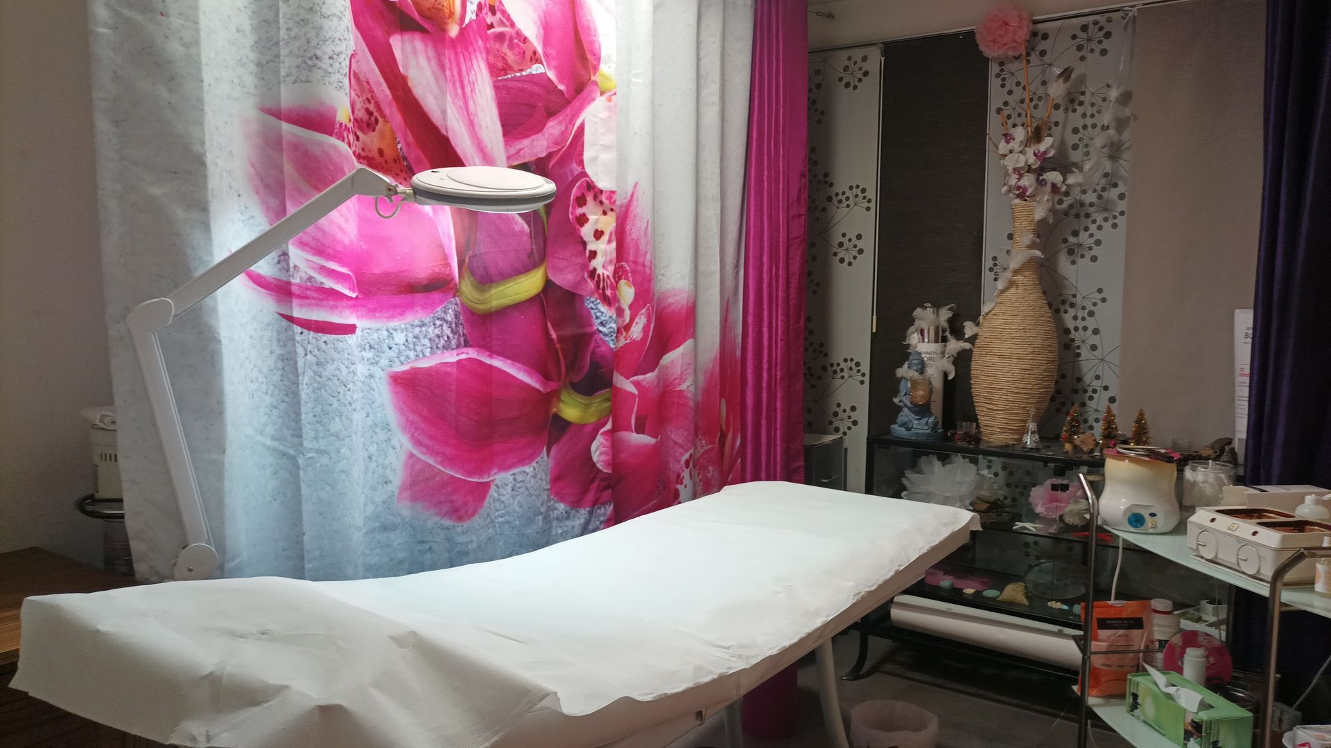 Salle de soins esthétique avec une table de massage, du matériel professionnel et une décoration murale colorée.