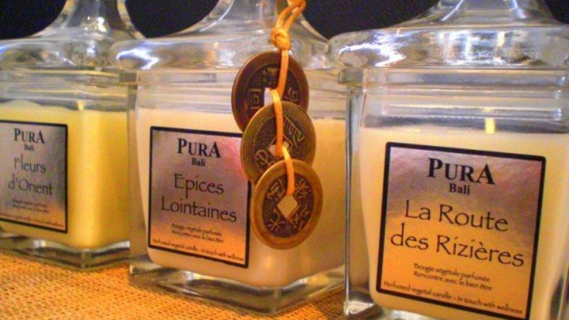 Trois bougies parfumées Pura Bali en pots en verre, ornées de pièces décoratives.