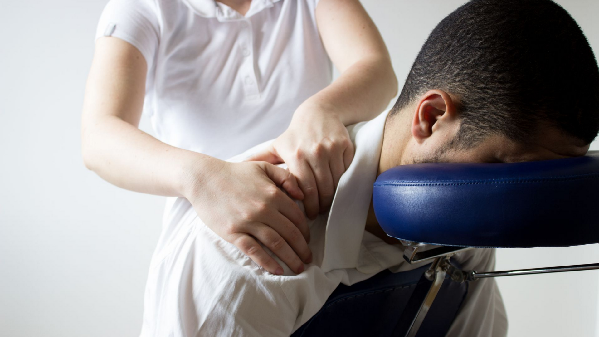 Massage des épaules réalisé sur une personne assise sur une chaise de massage.