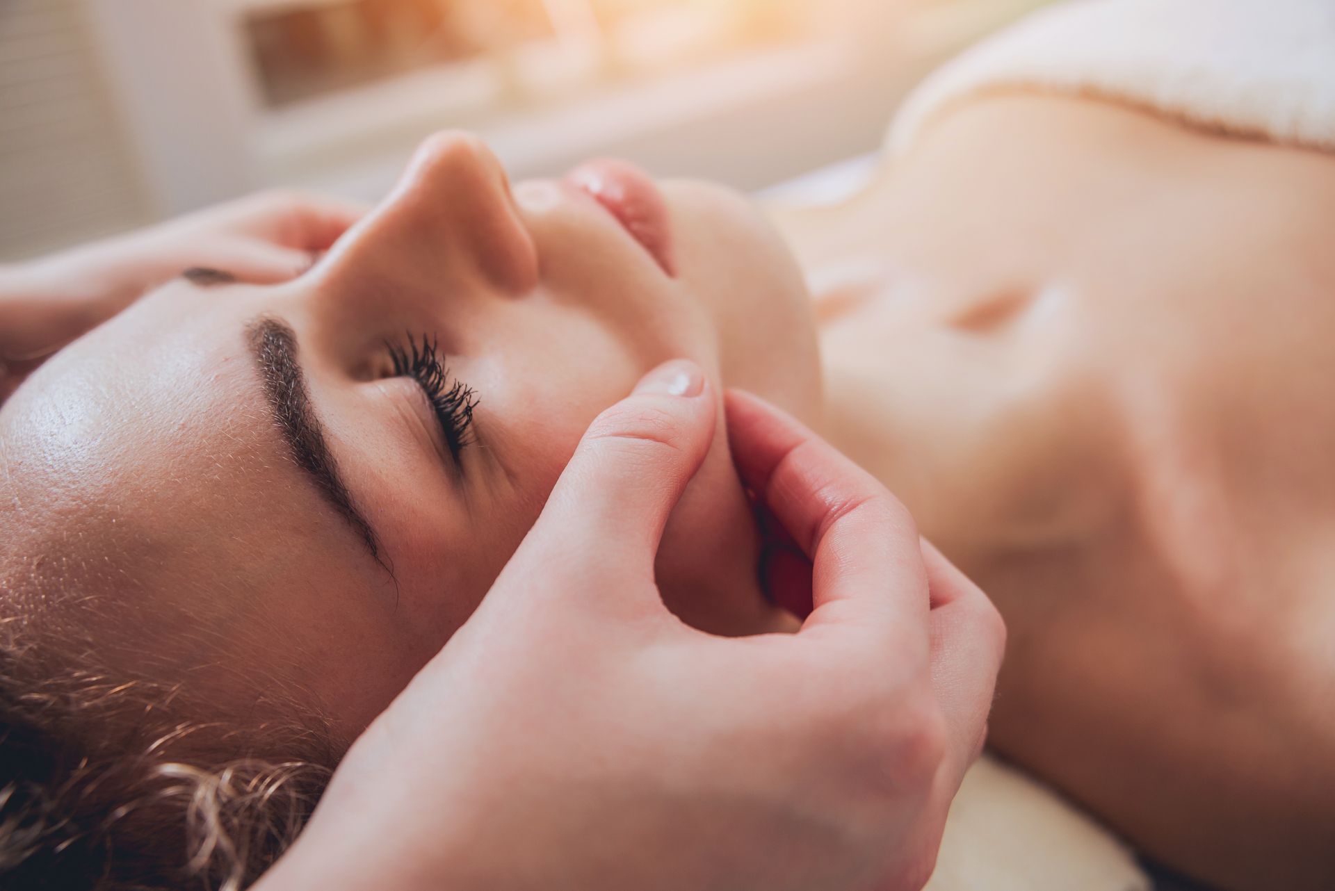 Salle de soins zen avec table de massage, éclairage doux, étagère de produits bien‑être et décor asiatique.
