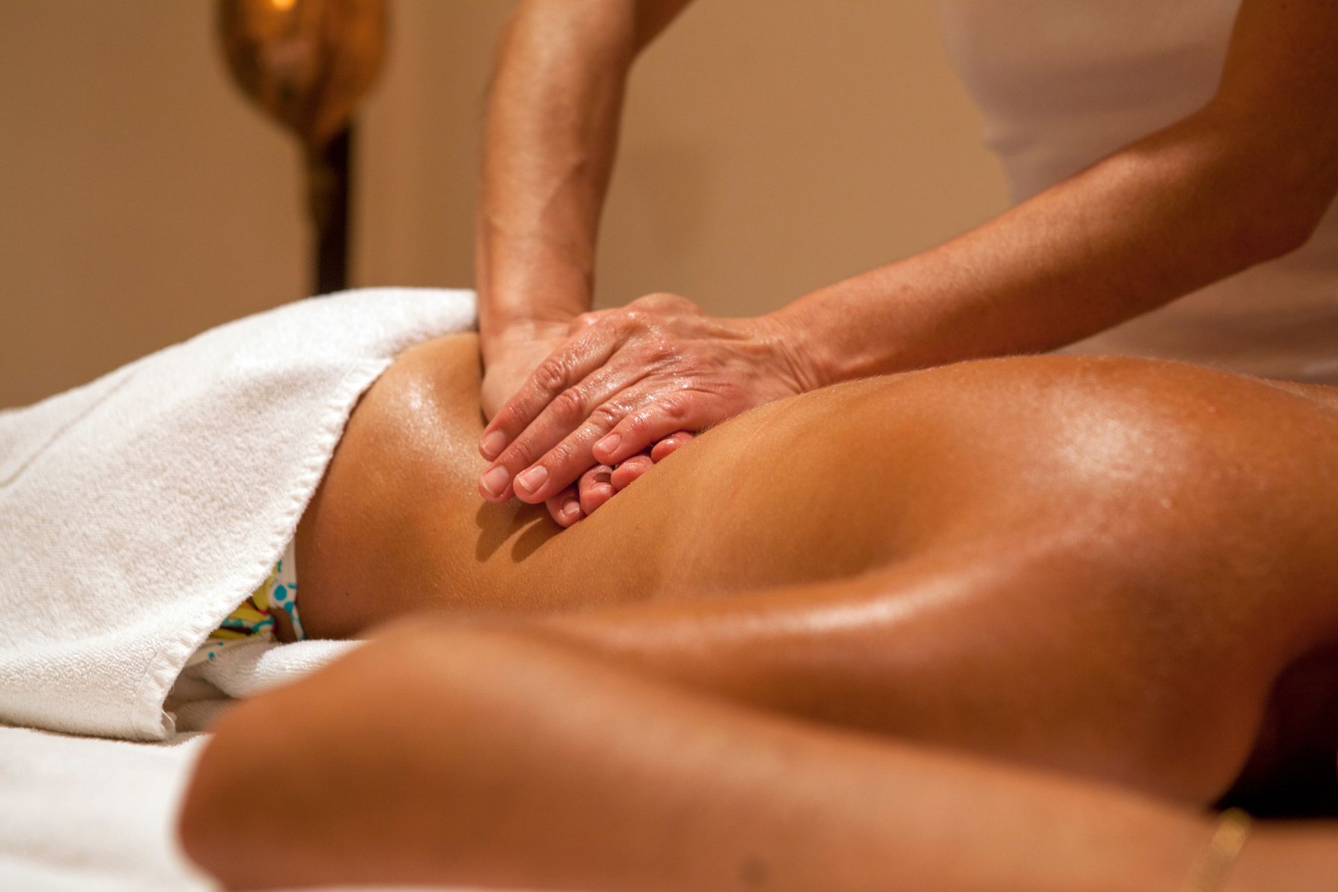 Une personne reçoit un massage du dos dans un spa professionnel à l'ambiance chaleureuse.