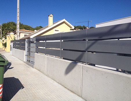 Una valla con una casa amarilla al fondo