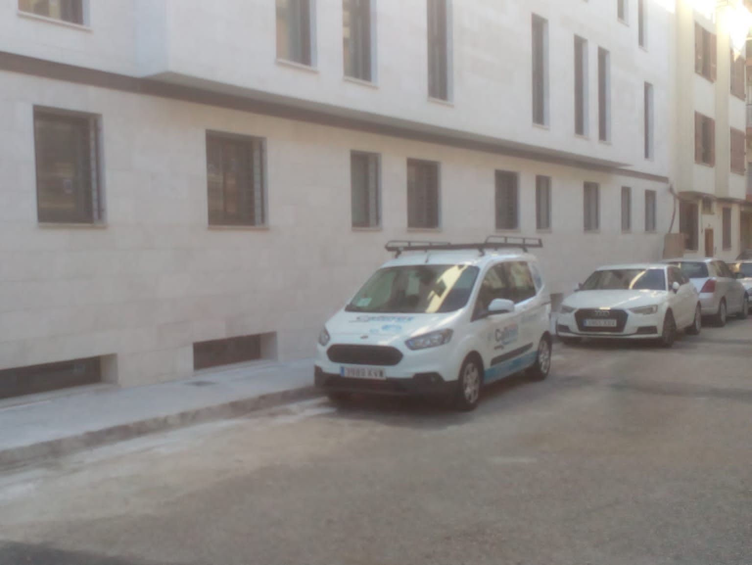 Una camioneta blanca está estacionada frente a un edificio