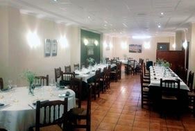 Comedor vacío de un restaurante con mesas cuidadosamente dispuestas y manteles blancos sobre un suelo de baldosas.