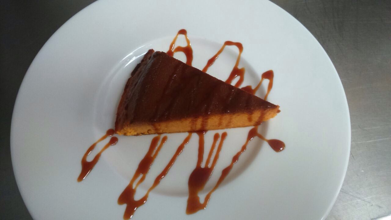Rebanada de pastel de chocolate en un plato blanco con sirope de caramelo.