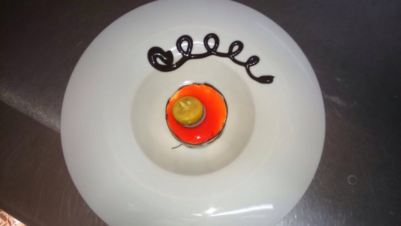 Objeto circular blanco con un centro rojo anaranjado y un cordón rizado negro en la parte superior, sobre una superficie oscura.