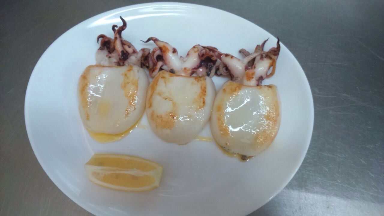 Tres huevos fritos y una rodaja de limón en un plato blanco.