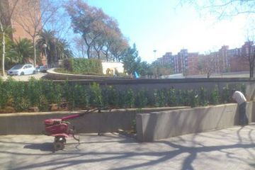 Un hombre está parado junto a un tractor rojo en un parque.