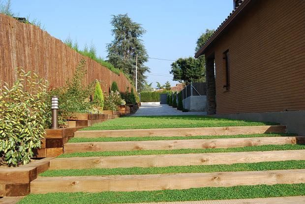 Una pasarela de madera que conduce a una casa con césped al costado.