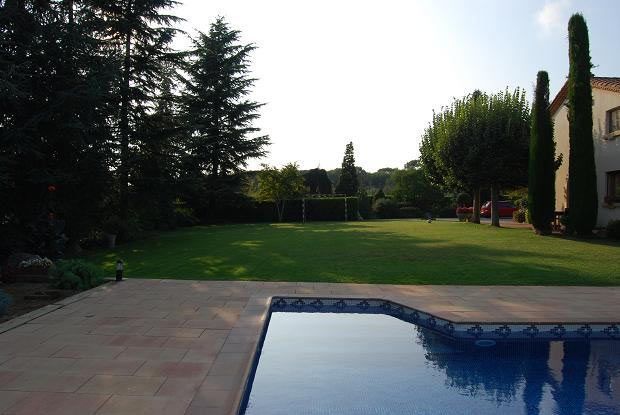 Un gran césped con una piscina en primer plano