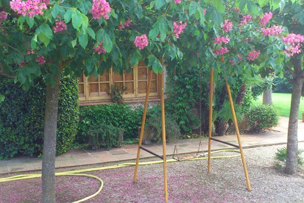 Un columpio está sentado debajo de un árbol con flores rosas.