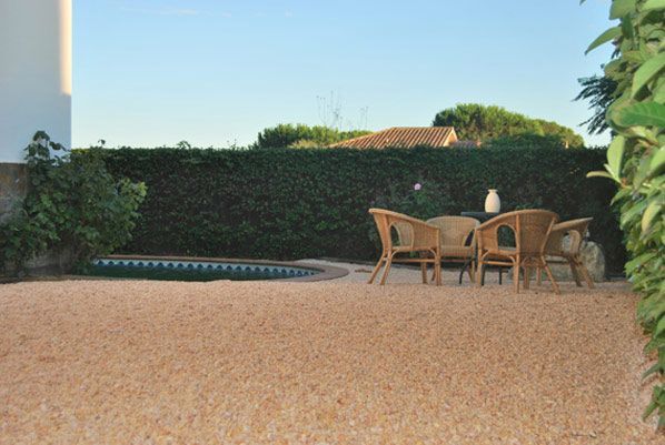Un patio con sillas y una mesa frente a una piscina.