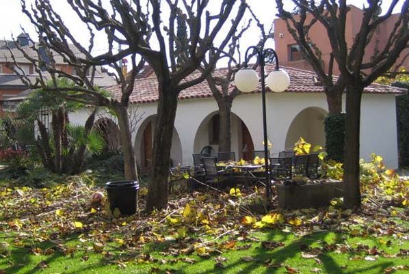 Un edificio blanco con arcos está rodeado de árboles y hojas.