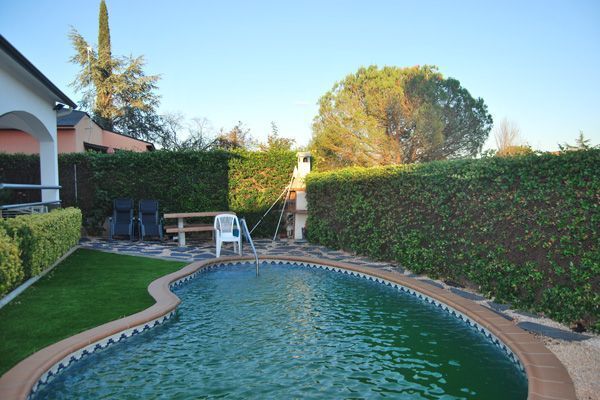 Una gran piscina está rodeada por un exuberante seto verde.