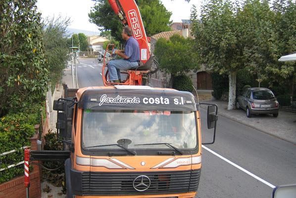 Un hombre está sentado encima de un camión naranja que dice costa sj