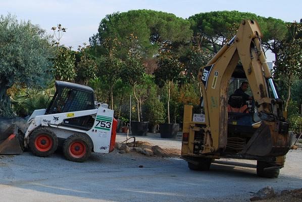 Un bobcat y una retroexcavadora están estacionados uno al lado del otro