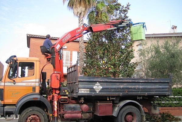 Un hombre está sentado encima de un camión naranja con una grúa adjunta.