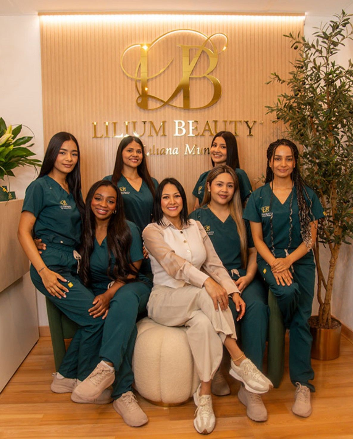 Un equipo de mujeres con uniformes verdes y una en color beige, posando en un entorno de clínica de belleza.