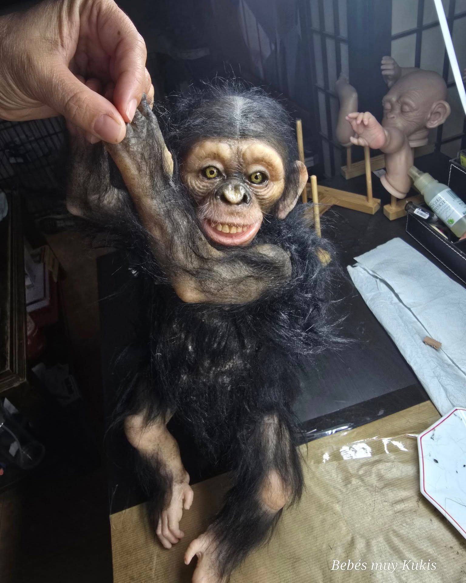 Una persona sostiene un chimpancé de peluche sobre una mesa.