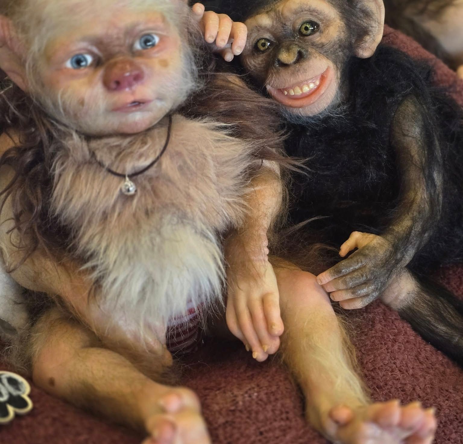 Dos monos de peluche están sentados uno al lado del otro sobre una alfombra.