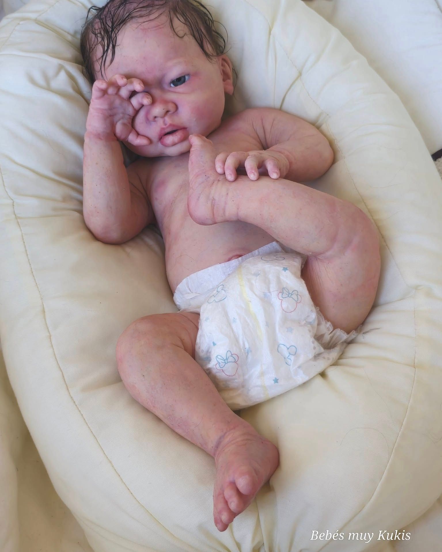 Una muñeca bebé con pañal está acostada sobre una almohada.