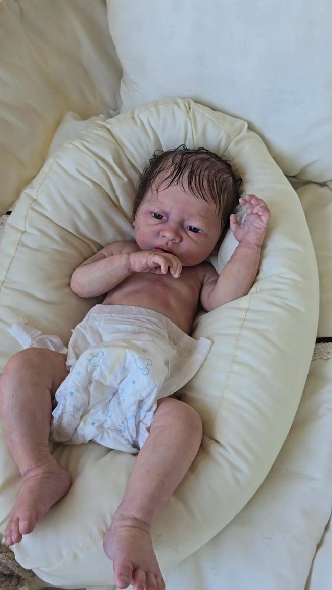 Un bebé con pañal está acostado sobre una almohada.