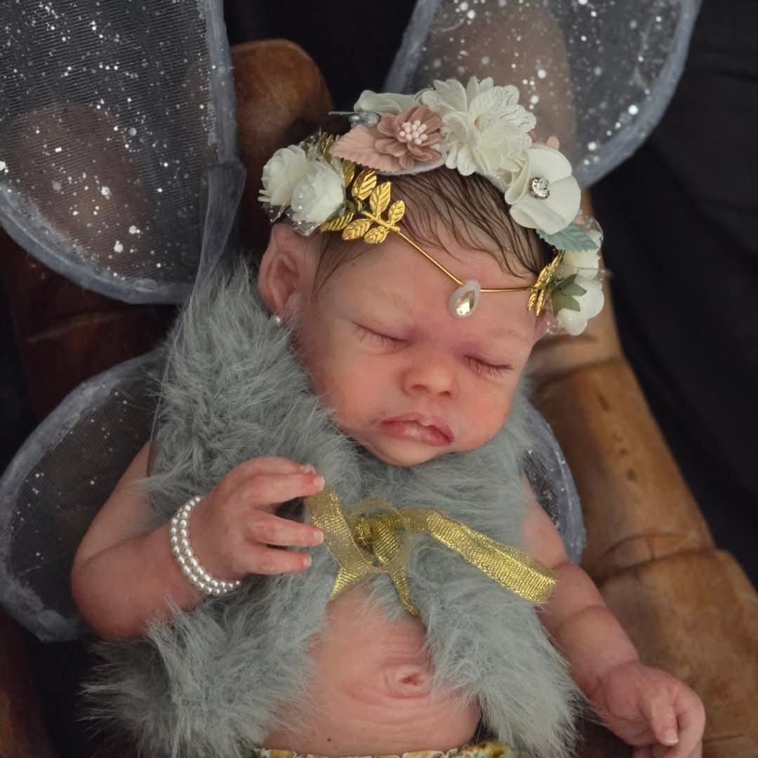 Una muñeca bebé con pañal está acostada sobre una almohada.